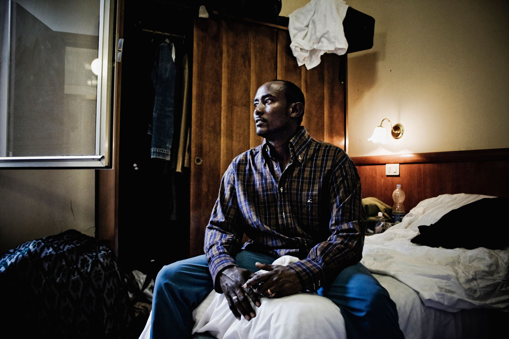 ITALY. Florence, 2nd July 2010. A Somali refugee sits inside his room in a shelter for refugees located in the building of the former "Hotel Real" in the outskirts of the city.