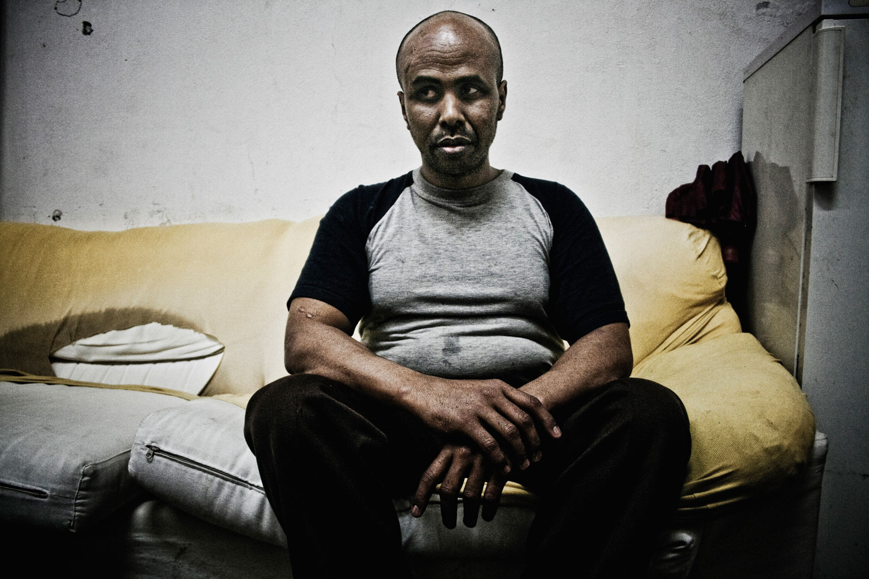 ITALY. Florence, 11th May 2010. A Somali refugee sits inside the "Kulanka" building, a former warehouse near the railways, occupied in 2008 by a group of Somali refugees with the support of an association that helps people without an house to live in. In 2009, according to a deal signed with the city mayor, the building has been loan for free temporary use to an association of Somali refugees. "Kulanka" means assembly in Somali language.