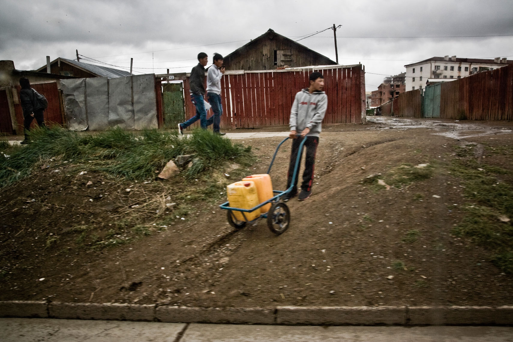 MONGOLIA. Ulan Bator, September 2012. Near Gandantegchinlen Monastery. A boy carrying home a water tank. Not every house, even in the city center like here, has running water inside.