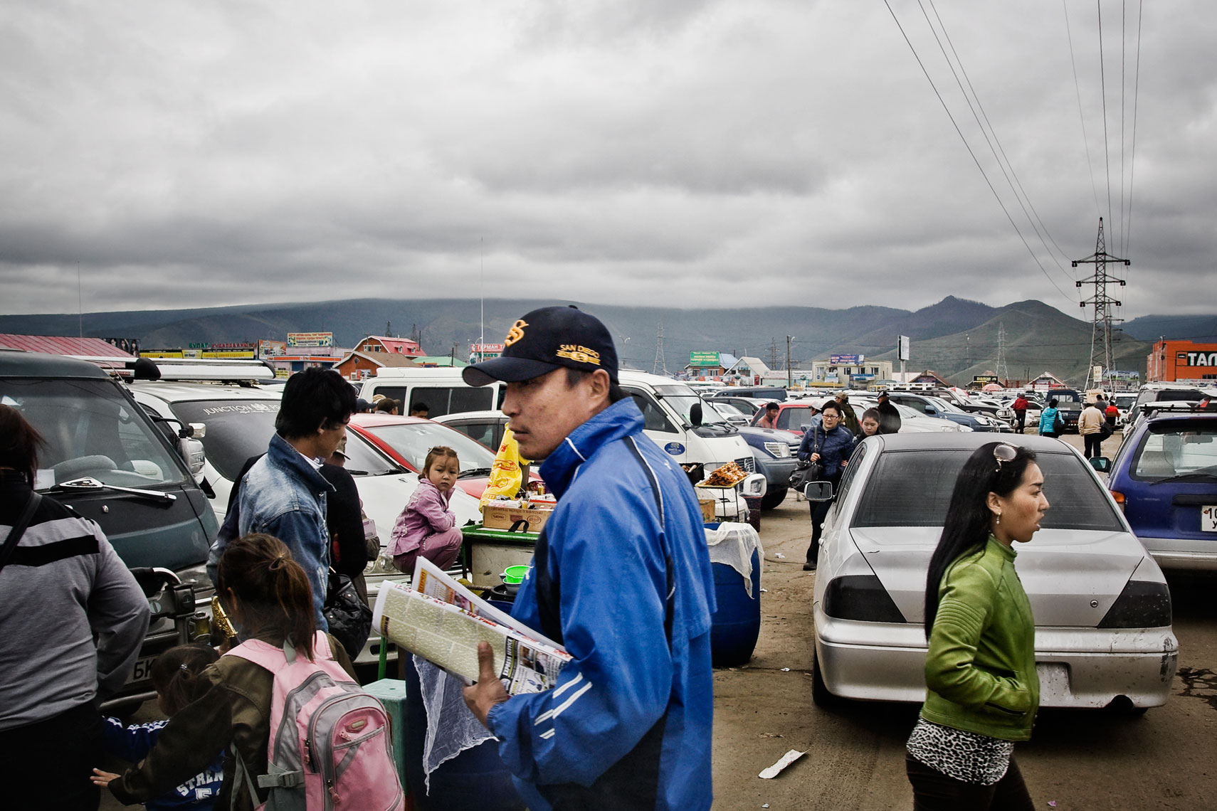 MONGOLIA. Ulan Bator, 2012. People in the parking lot of the Black Market. The market, despite the name, a legal one, is the biggest in Mongolia. Inside it is possible to buy goods and tools useful for the nomadic life in open territories.