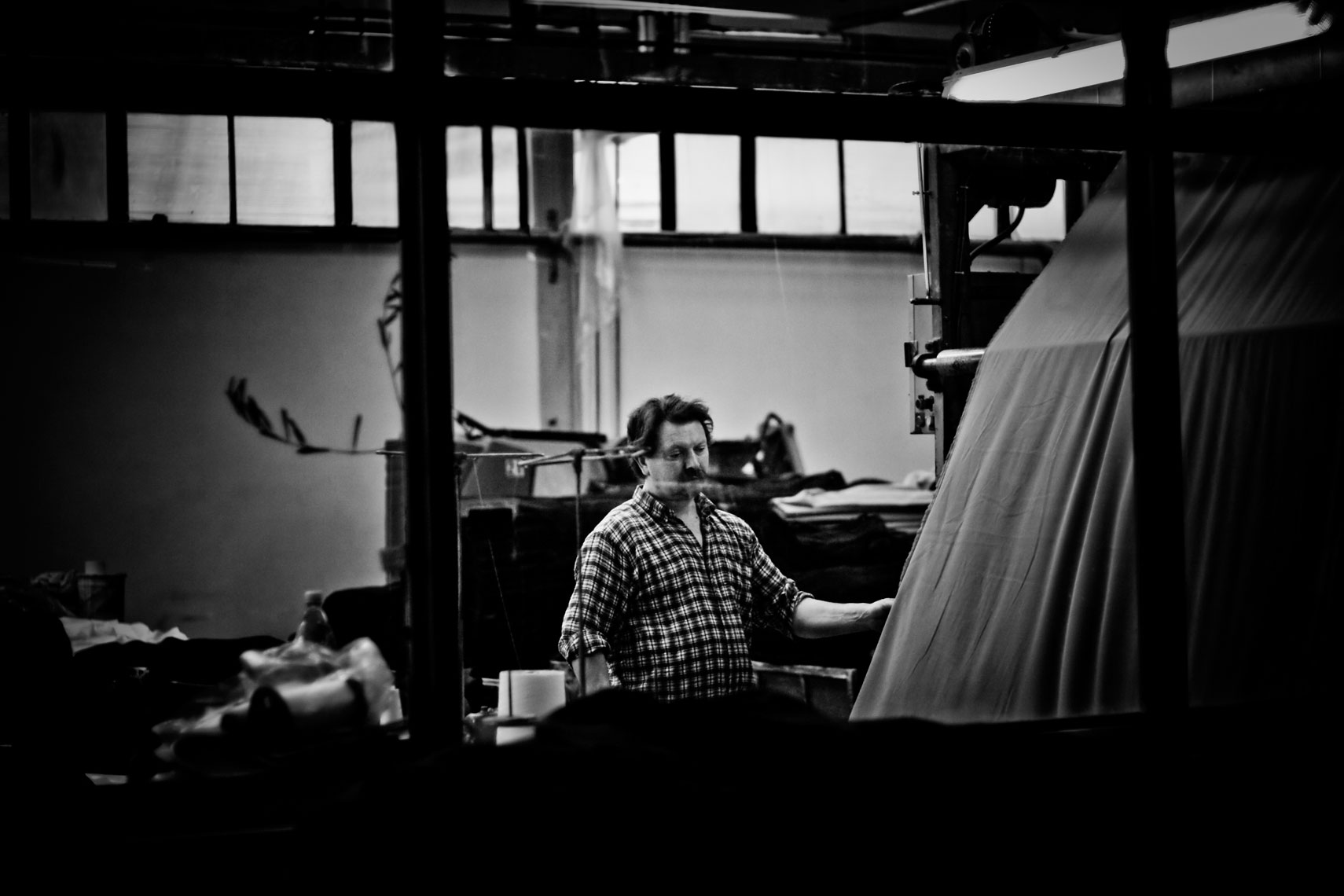 ITALY. Prato, 31st March 2009. Worker using finishing machines.