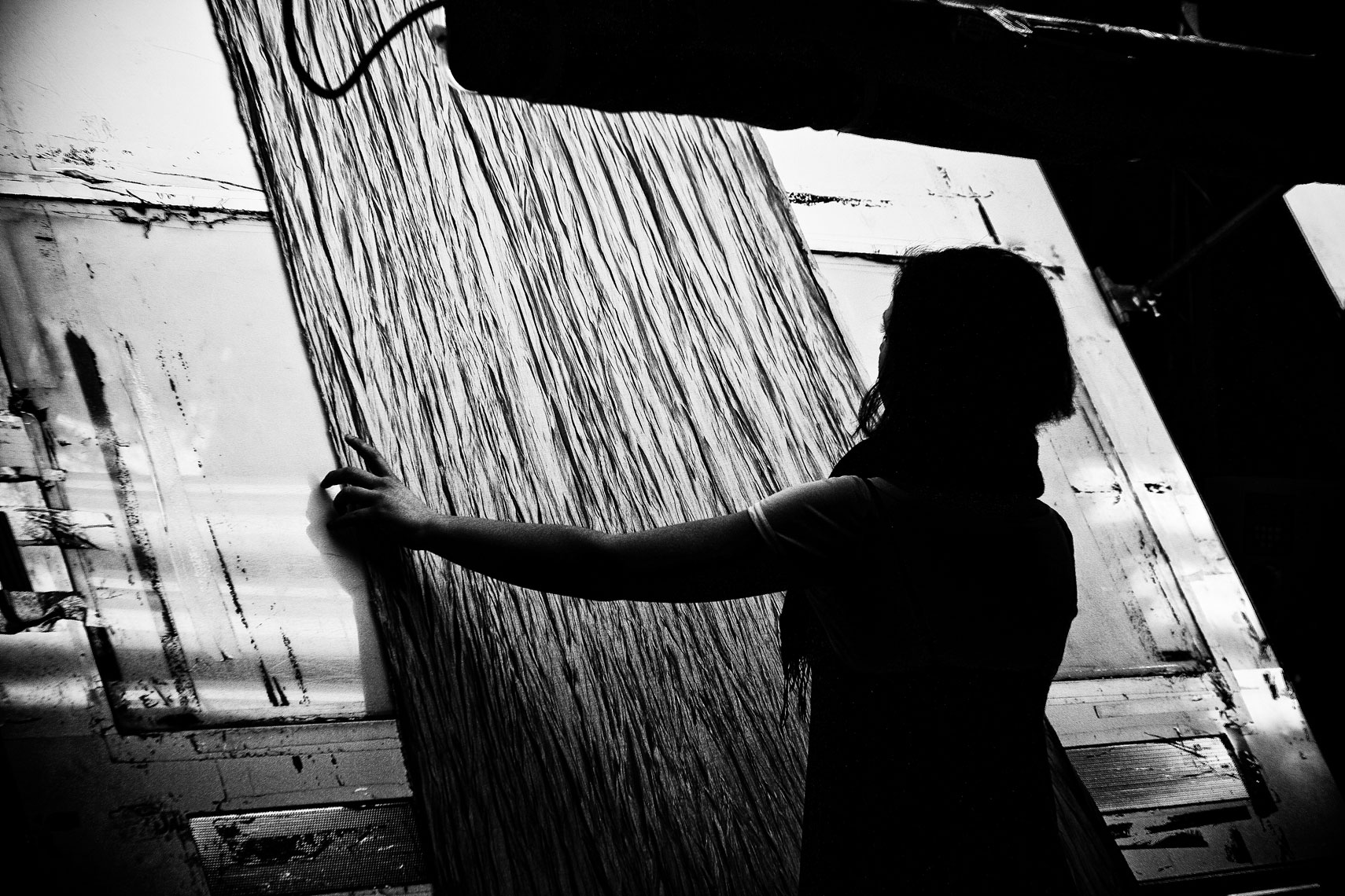 ITALY. Prato, 31st March 2009. A worker checks the quality of a fabric on a so-called "mirror".