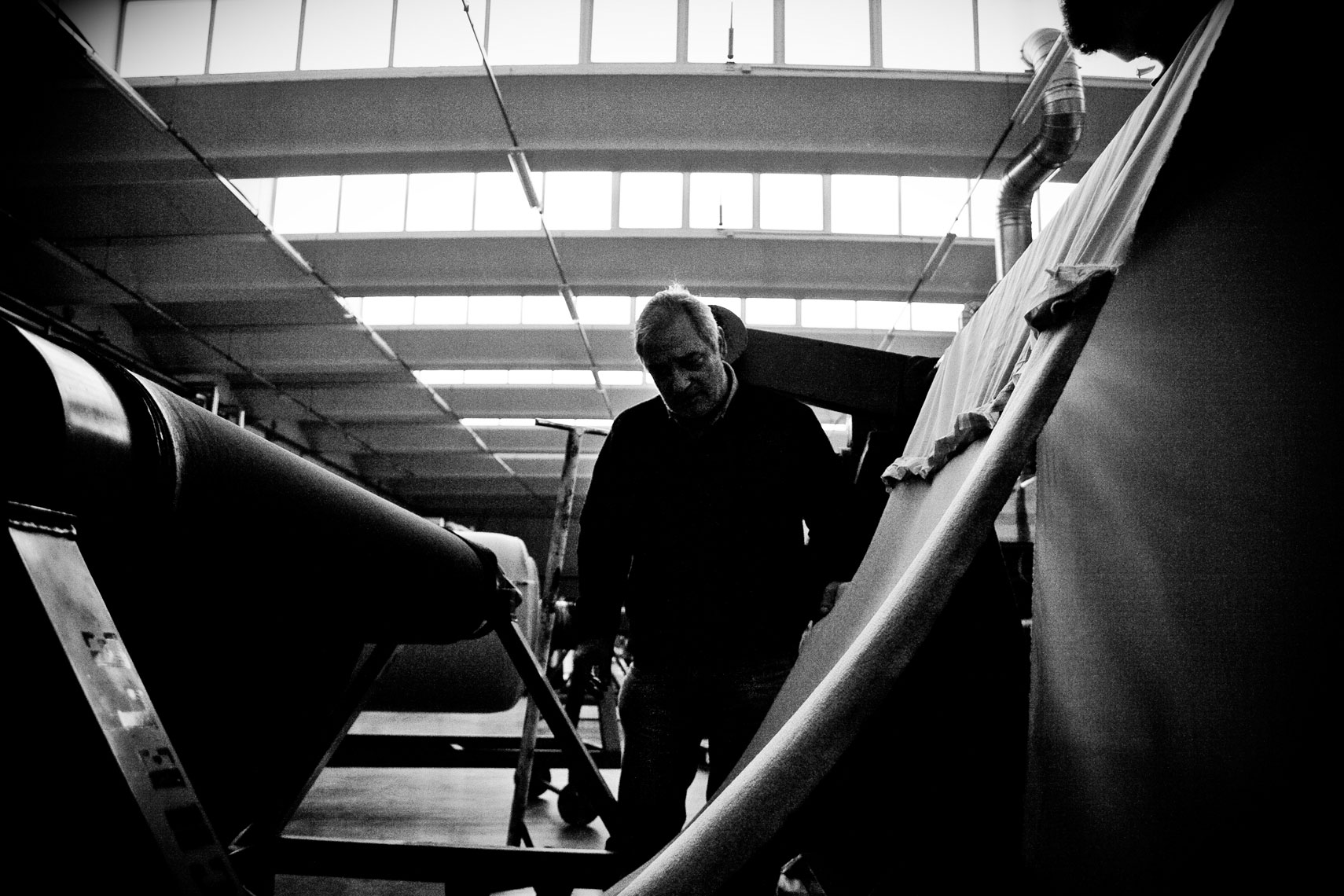 ITALY. Montemurlo (Prato), 2nd April 2009. A worker checks the passage of a tissue through a finishing machine.